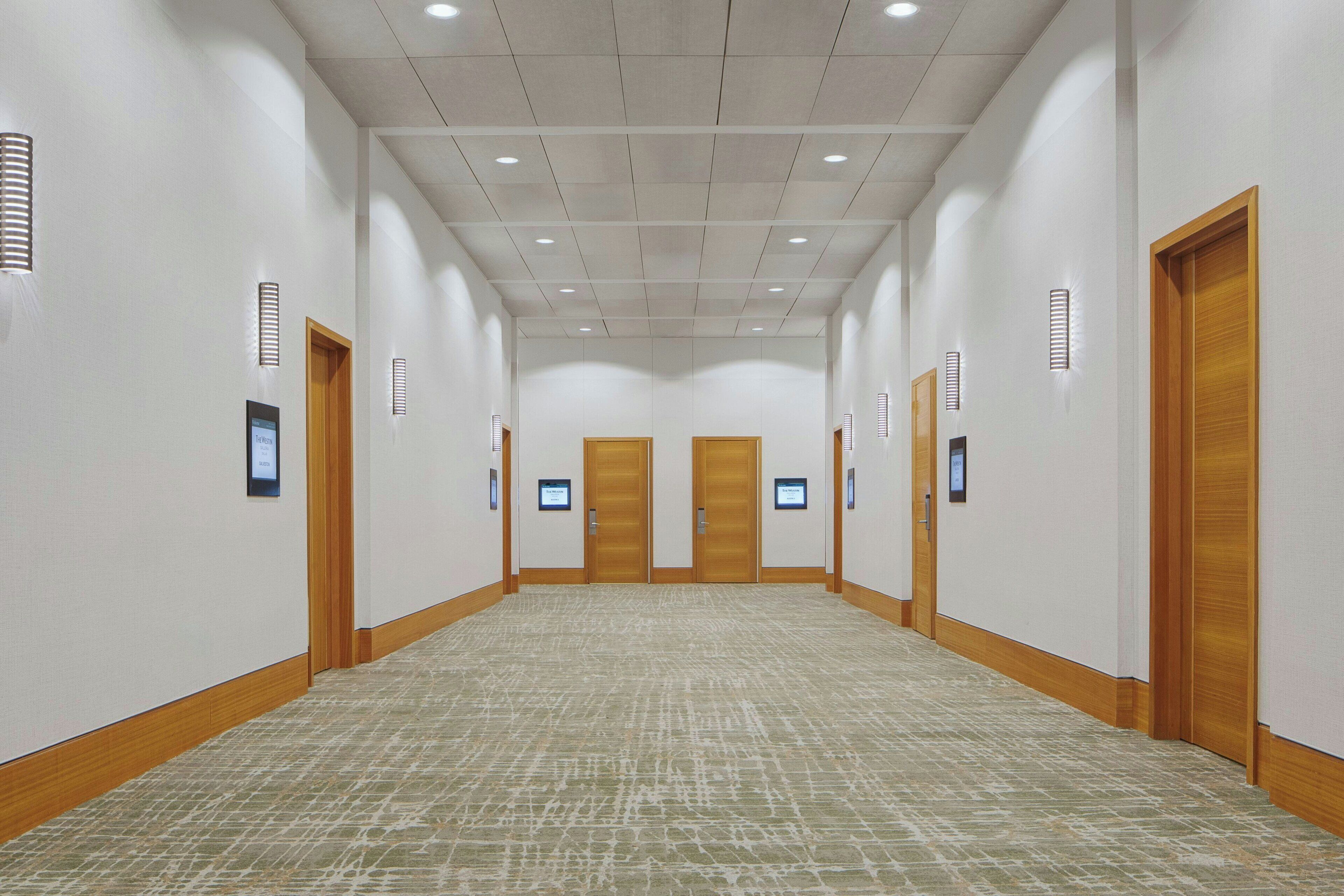 A long, narrow hotel corridor with wooden doors and recessed lighting.