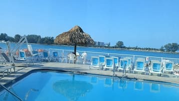 Una piscina al aire libre, sillones reclinables de piscina