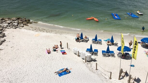 A beach with clear water, umbrellas, and chairs.
