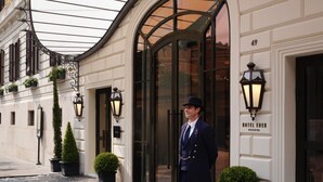 A hotel entrance with a curved facade, a large glass door, and a sign reading "HOTEL EDEN". - Hotel Eden - Dorchester Collection (Rome)