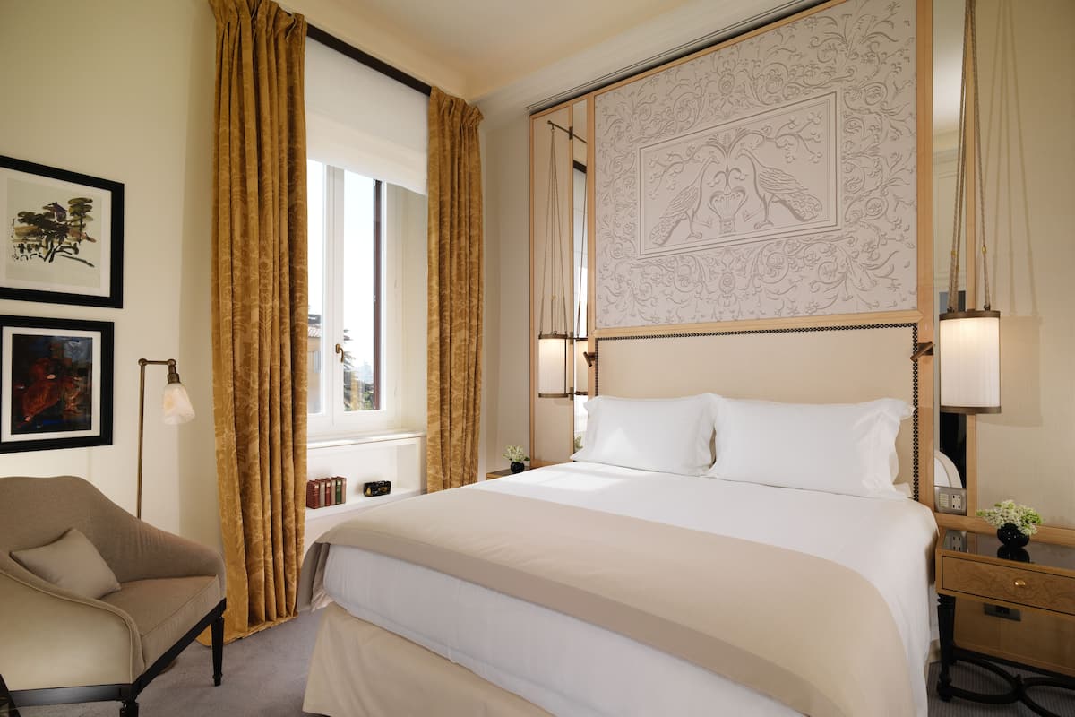 Habitación de hotel con una cama grande, una silla, una mesita de noche y una pared con un diseño ornamental.