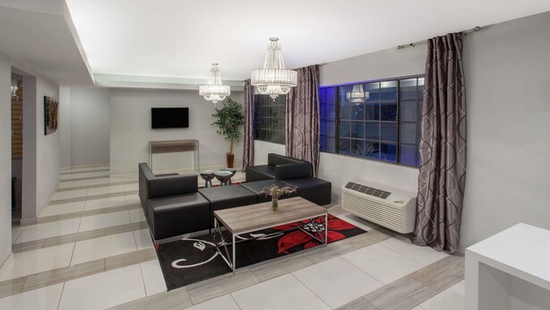 A modern living room with a sofa, coffee table, and chandelier. - Ramada by Wyndham Culver City (Culver City)