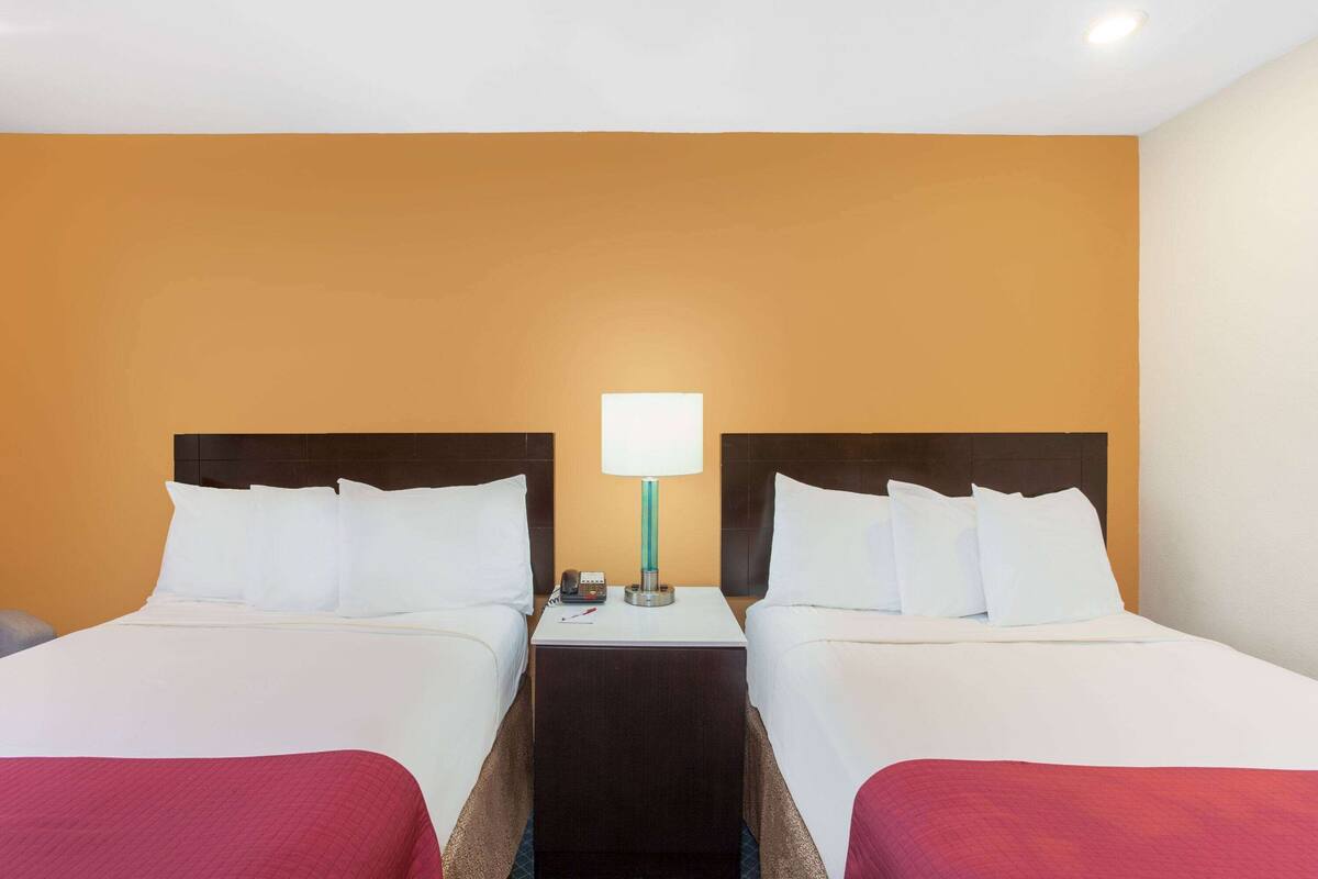Ein Hotelzimmer mit zwei Betten, einem Nachttisch mit Lampe und einem Telefon.