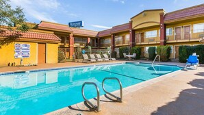 A hotel with a pool area, including lounge chairs and a sign for 'Rodeway Inn & Suites'. - Rodeway Inn & Suites Corona (Corona)
