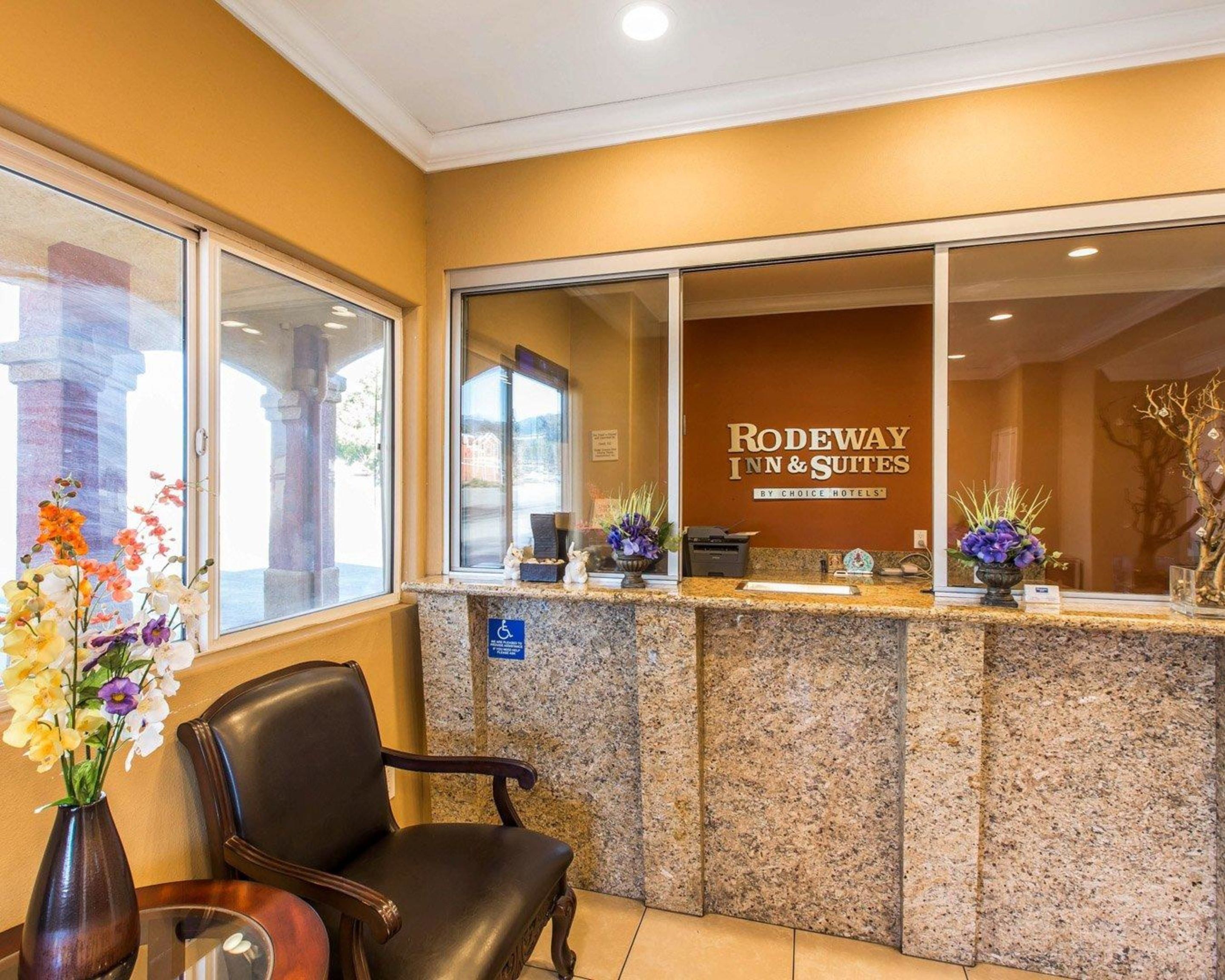A reception area with a reception desk, a chair, and a vase with flowers.
