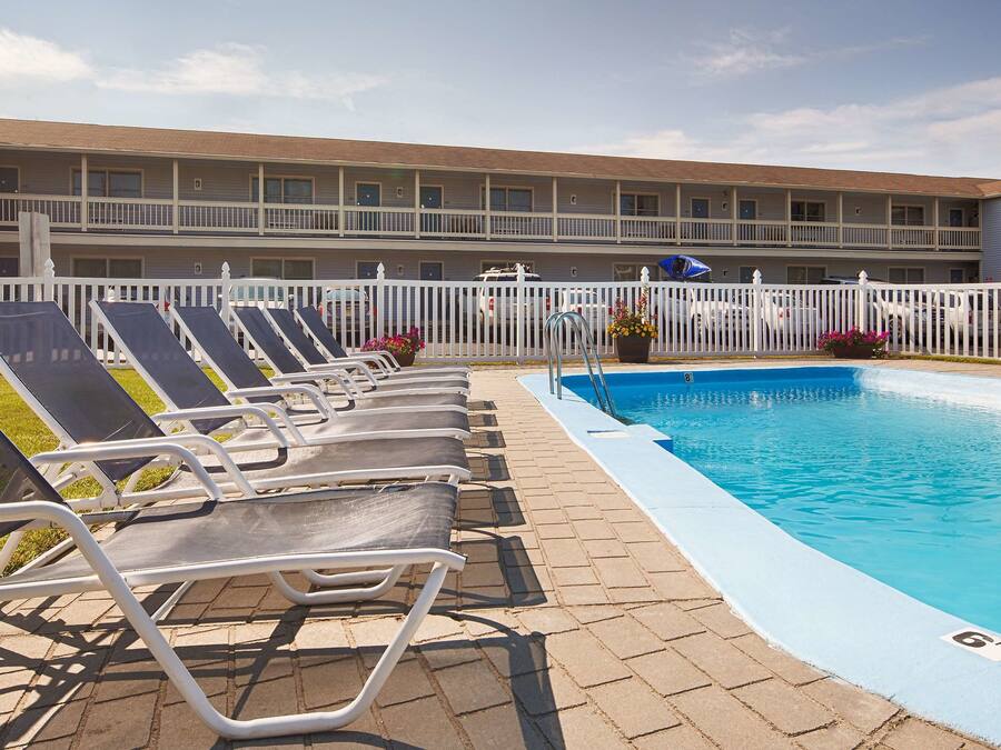 Uma área de piscina de hotel com espreguiçadeiras e uma piscina azul cristalina.