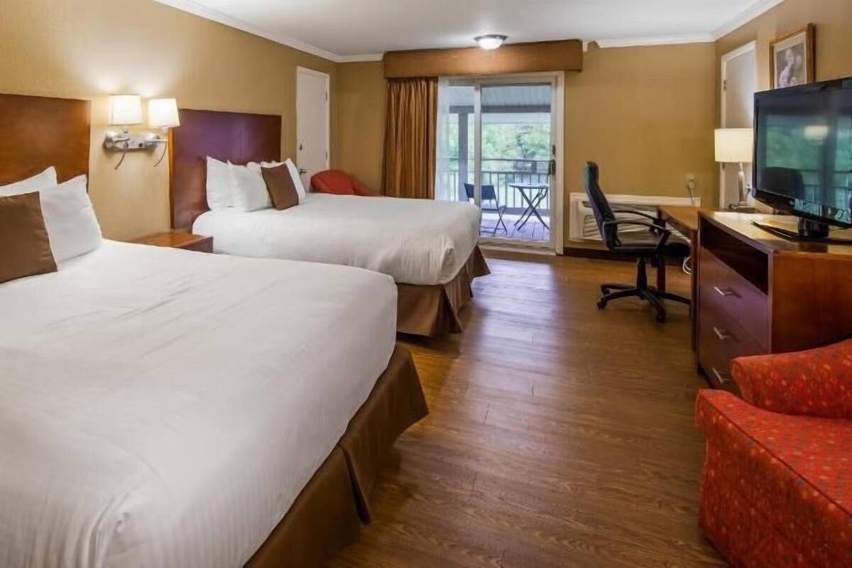 Una habitación de hotel con dos camas, un escritorio, un televisor y una silla.