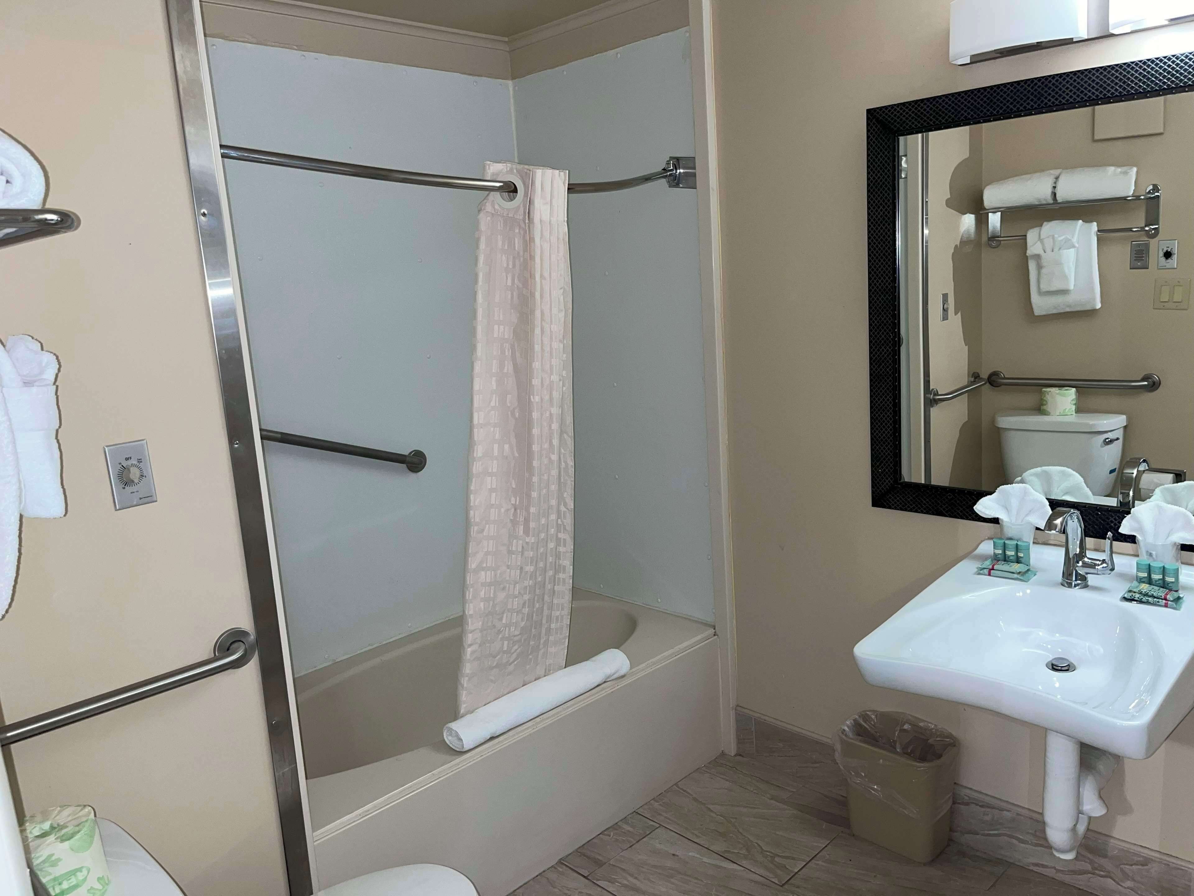 A bathroom with a bathtub, a toilet, a sink, a mirror, and a towel rack.
