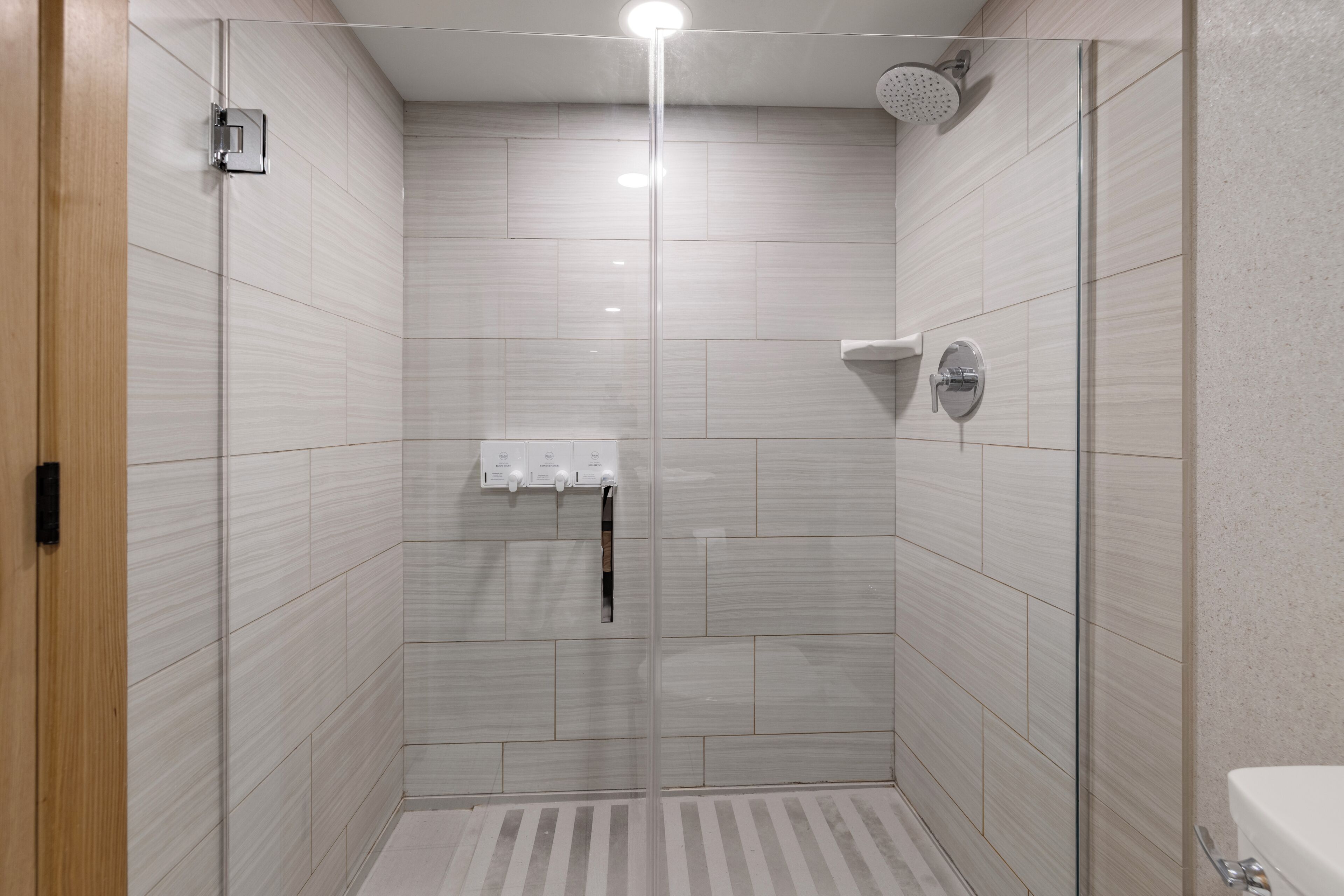 A modern shower stall with a glass door, a handheld showerhead, and a wall-mounted faucet.