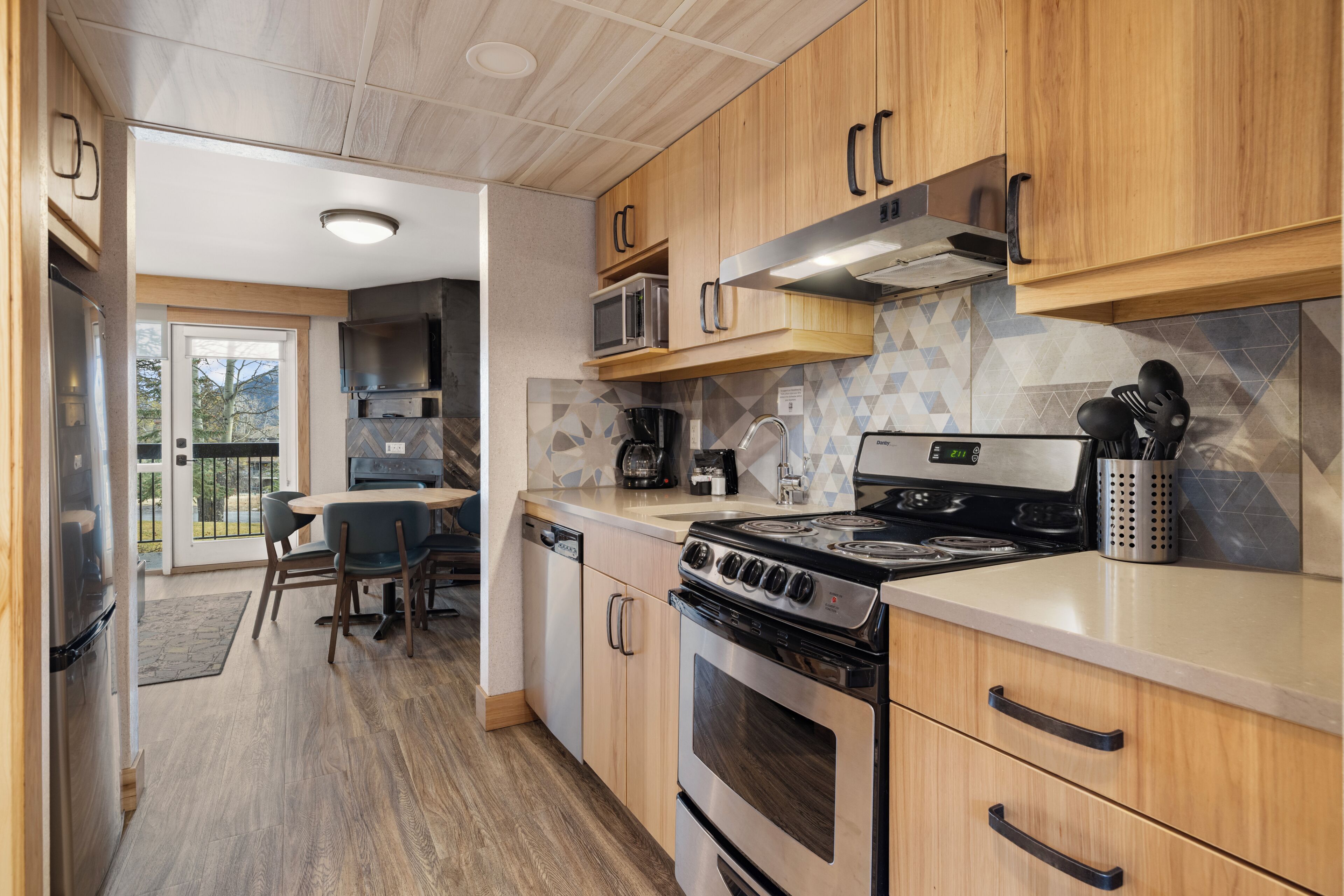 A modern kitchen with wooden cabinets, a built-in microwave, a stove, and a dishwasher.