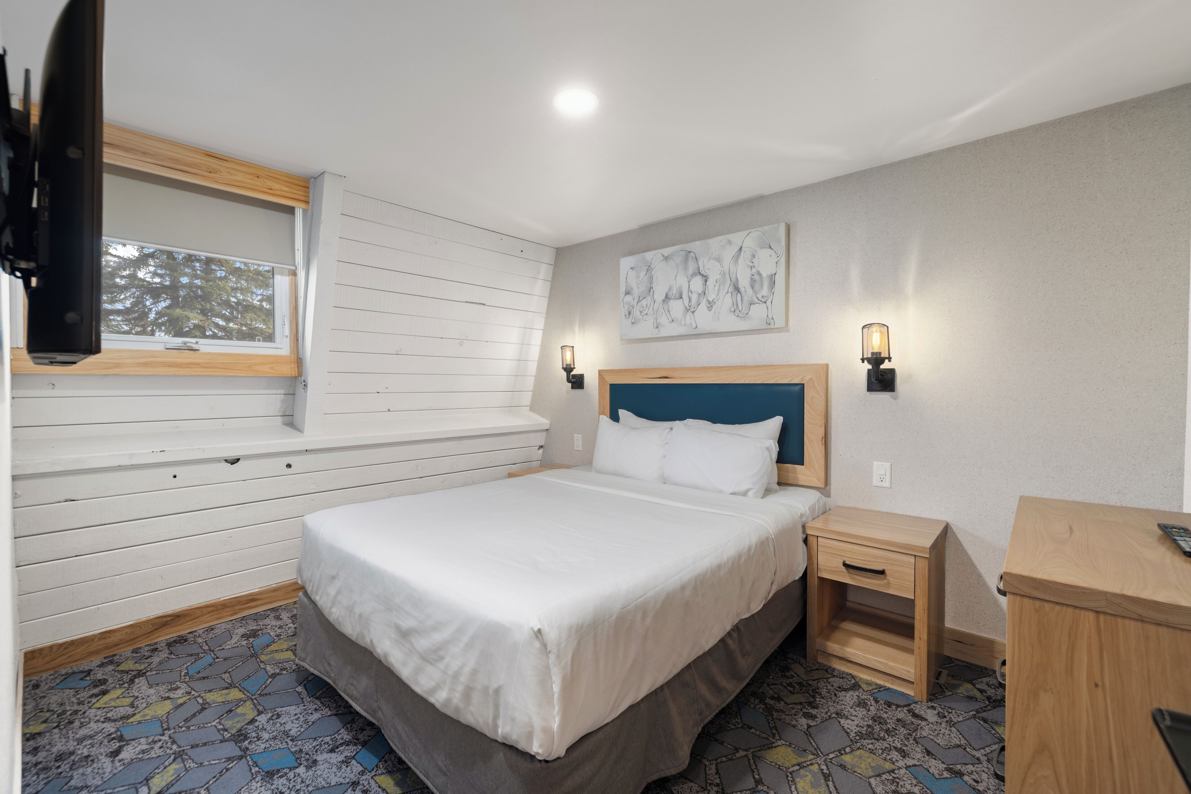 A bedroom with a bed, bedside tables, a window, and a wall-mounted artwork.