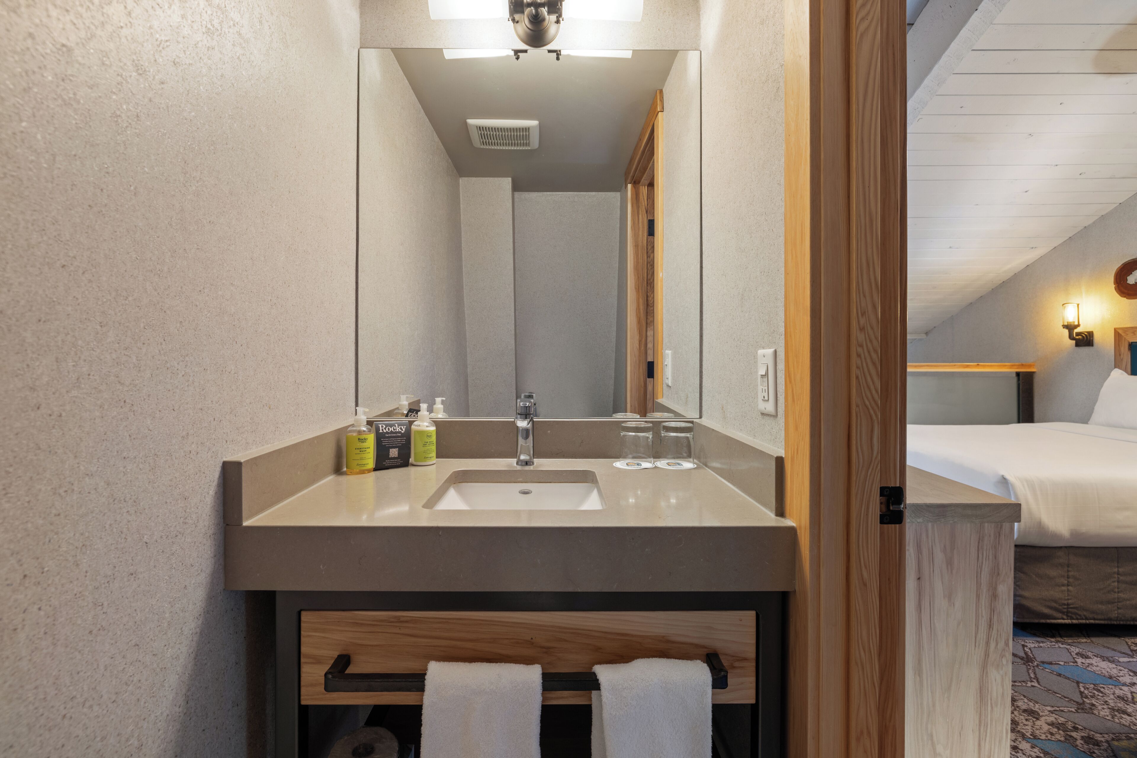 A modern bathroom with a large mirror, a sink, and a towel rack.