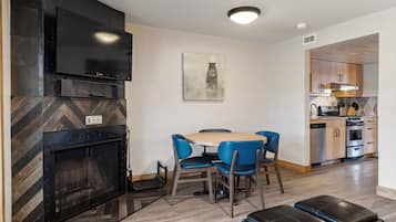 A modern kitchen with a built-in oven, a dining area with blue chairs, and a fireplace.