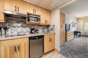 A modern kitchen with wooden cabinets, a built-in microwave, a coffee maker, and a dishwasher. - Tunnel Mountain Resort (Banff)