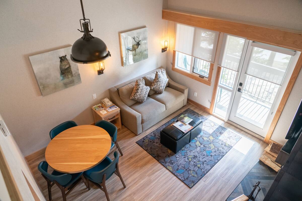 Una sala de estar acogedora con una mesa de comedor de madera, sillas azules, un sofá color beige y obras de arte en las paredes.