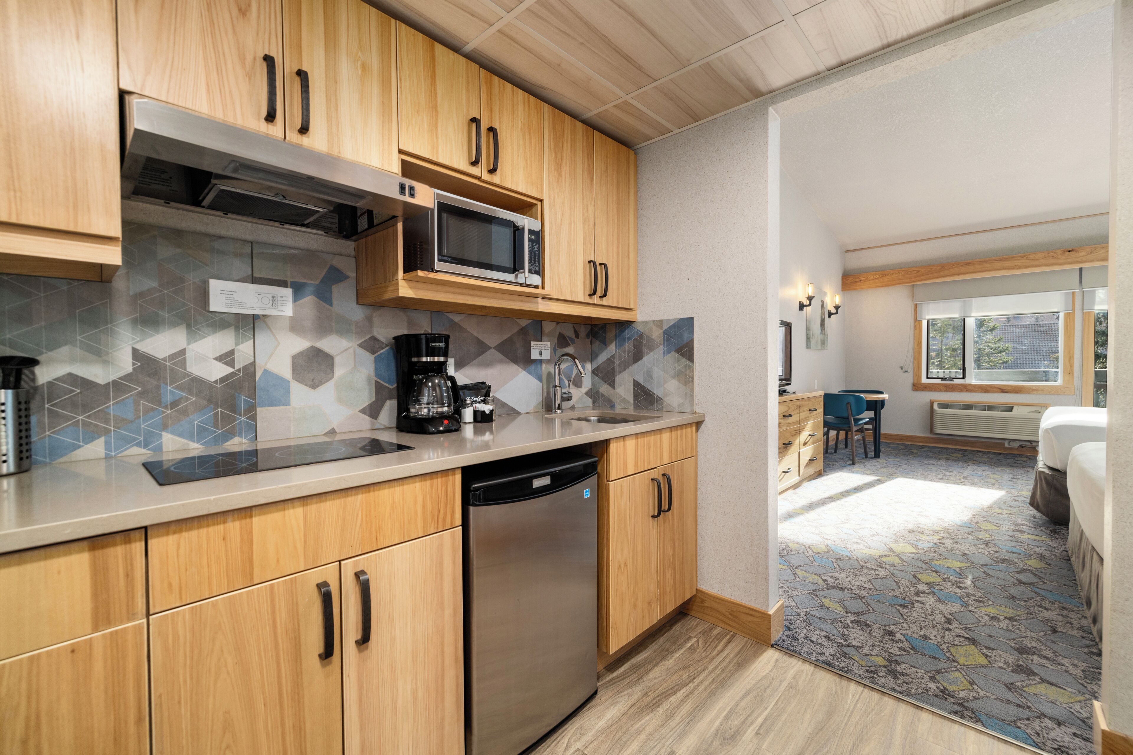 Een moderne keuken met houten kastjes, een RVS vaatwasser en een magnetron.