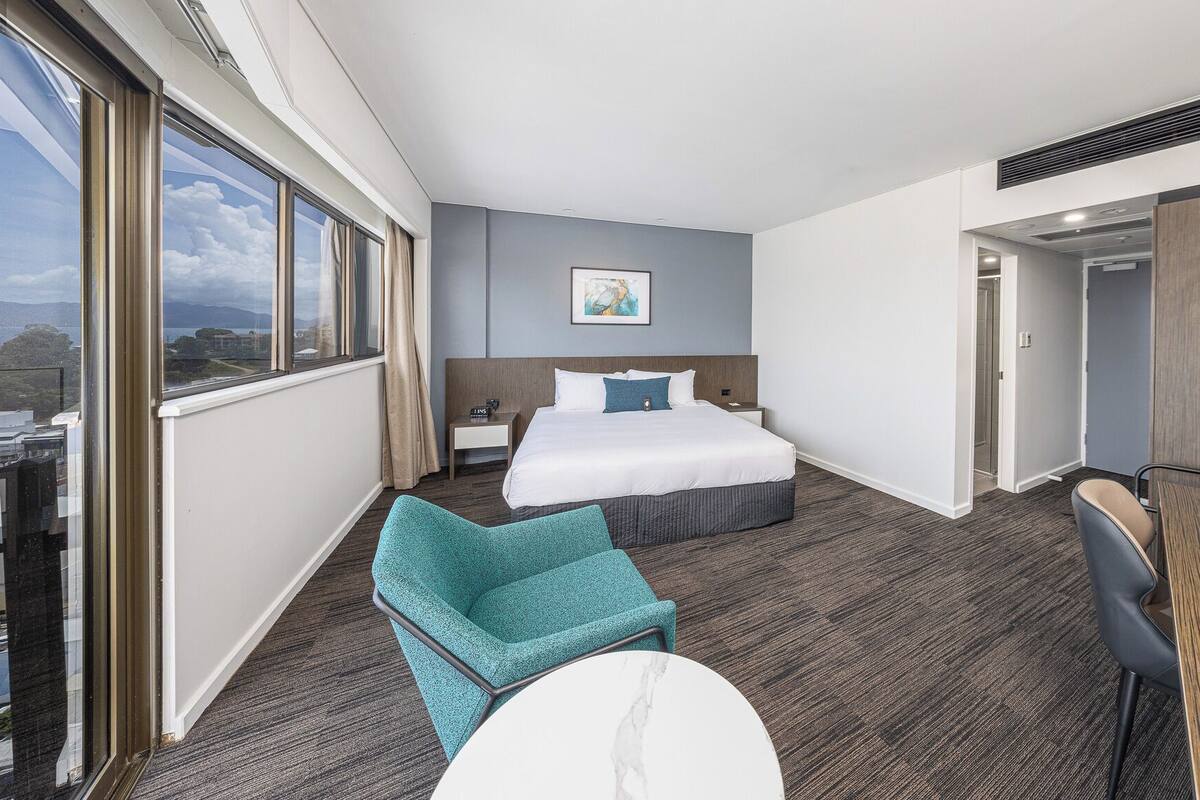 Une chambre d’hôtel avec un grand lit, un bureau, une chaise et une vue sur la ville.