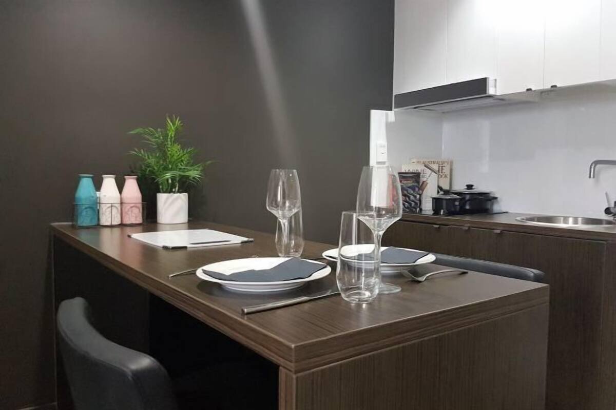Un coin repas avec une table en bois, des chaises, des assiettes, des verres et une plante en pot.