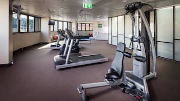 Une salle de sport équipée de tapis de course, d’une machine de musculation et de ballons d’exercice.