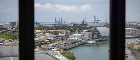A coastal cityscape with a marina, industrial cranes, and a bridge.