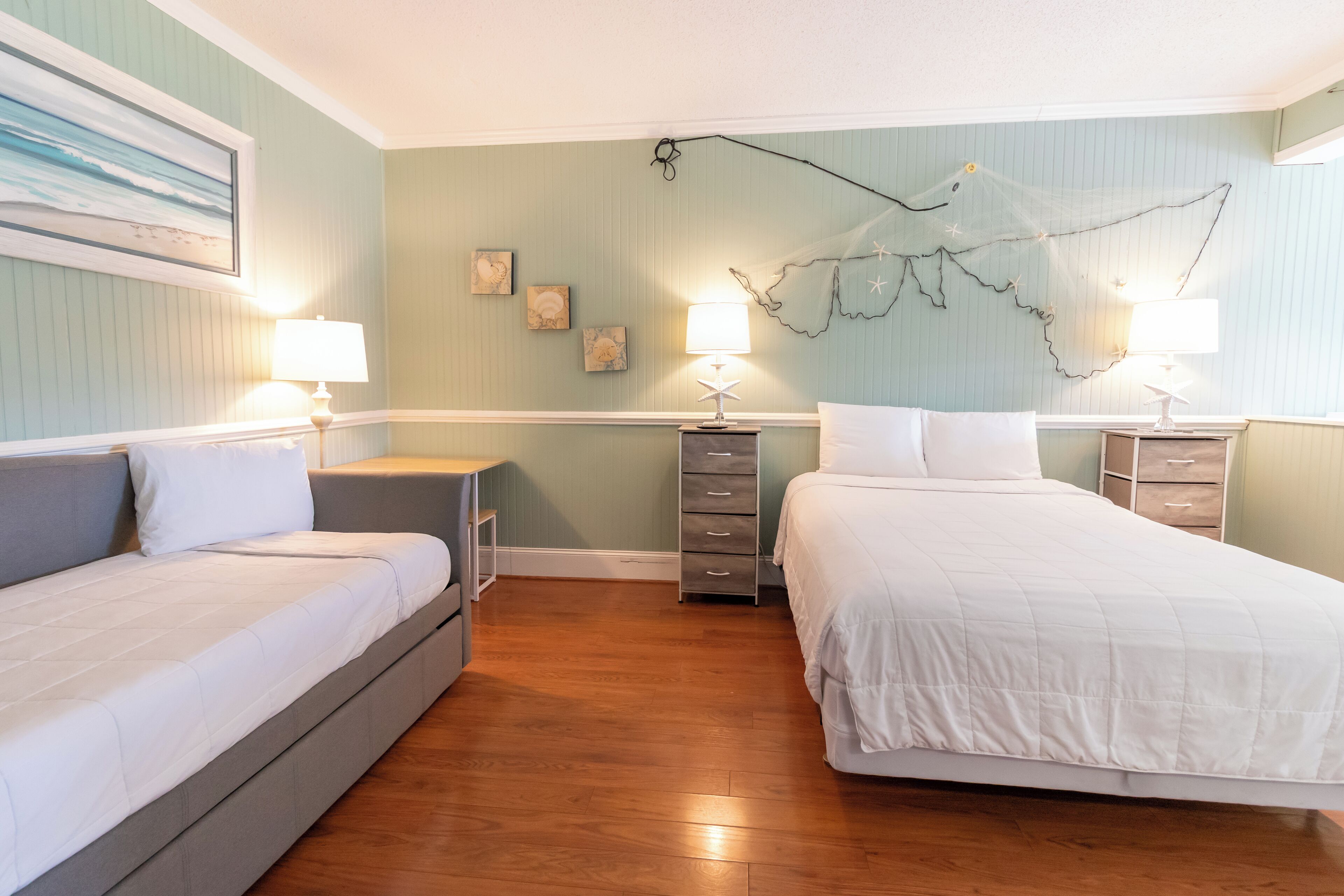 Un dormitorio con dos camas, una mesita de noche, un aparador y decoración en las paredes.