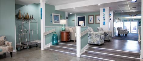A spacious lobby with a staircase, seating area, and artwork on the walls.