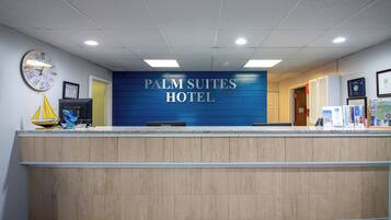 Uma receção com uma placa a indicar "PALM SUITES HOTEL" e um relógio na parede.