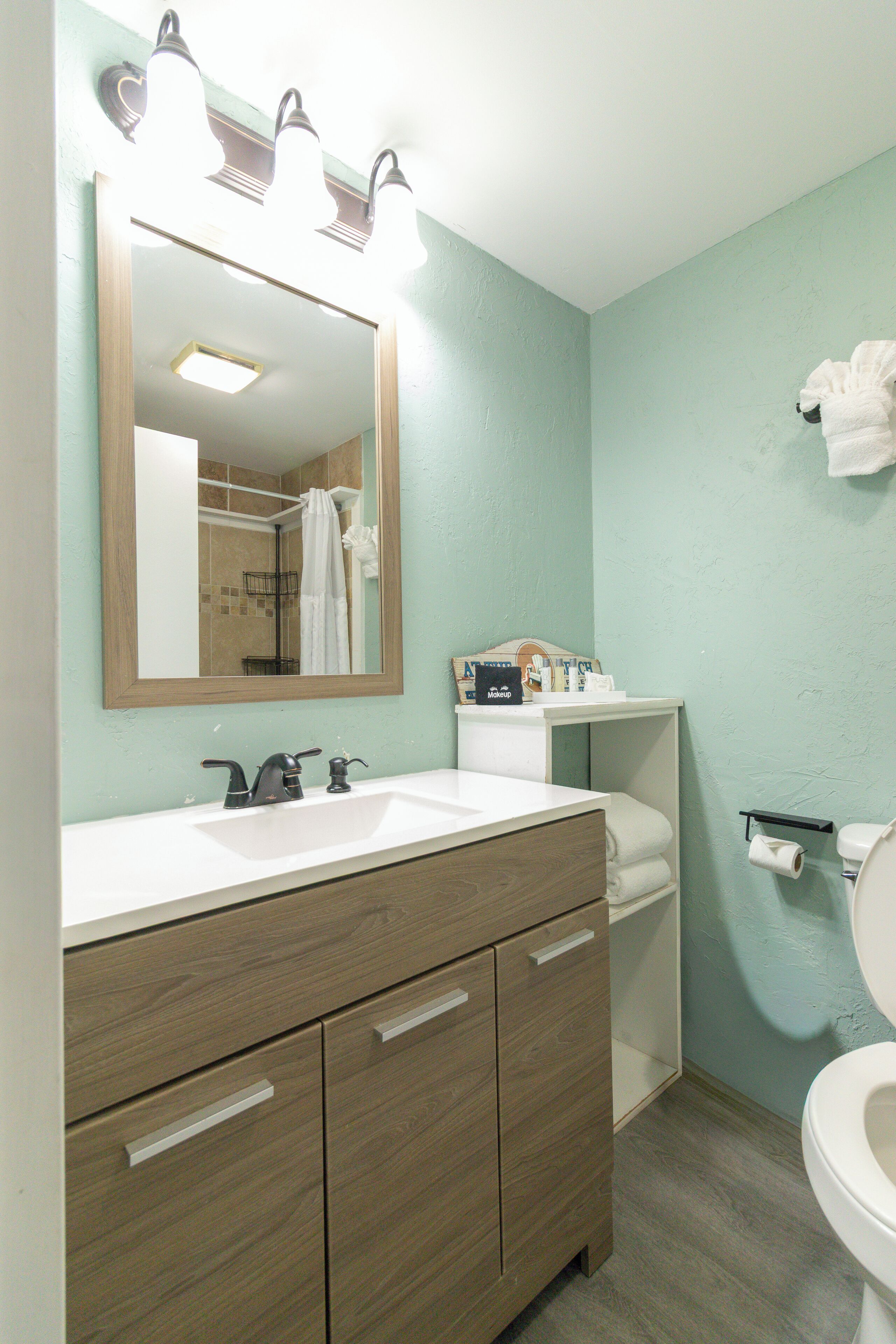 A bathroom with a wooden vanity, a mirror, a sink, and a toilet.