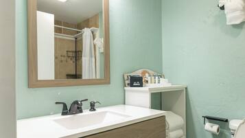 A bathroom with a wooden vanity, a mirror, a sink, and a toilet.