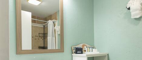 A bathroom with a wooden vanity, a mirror, a sink, and a toilet.