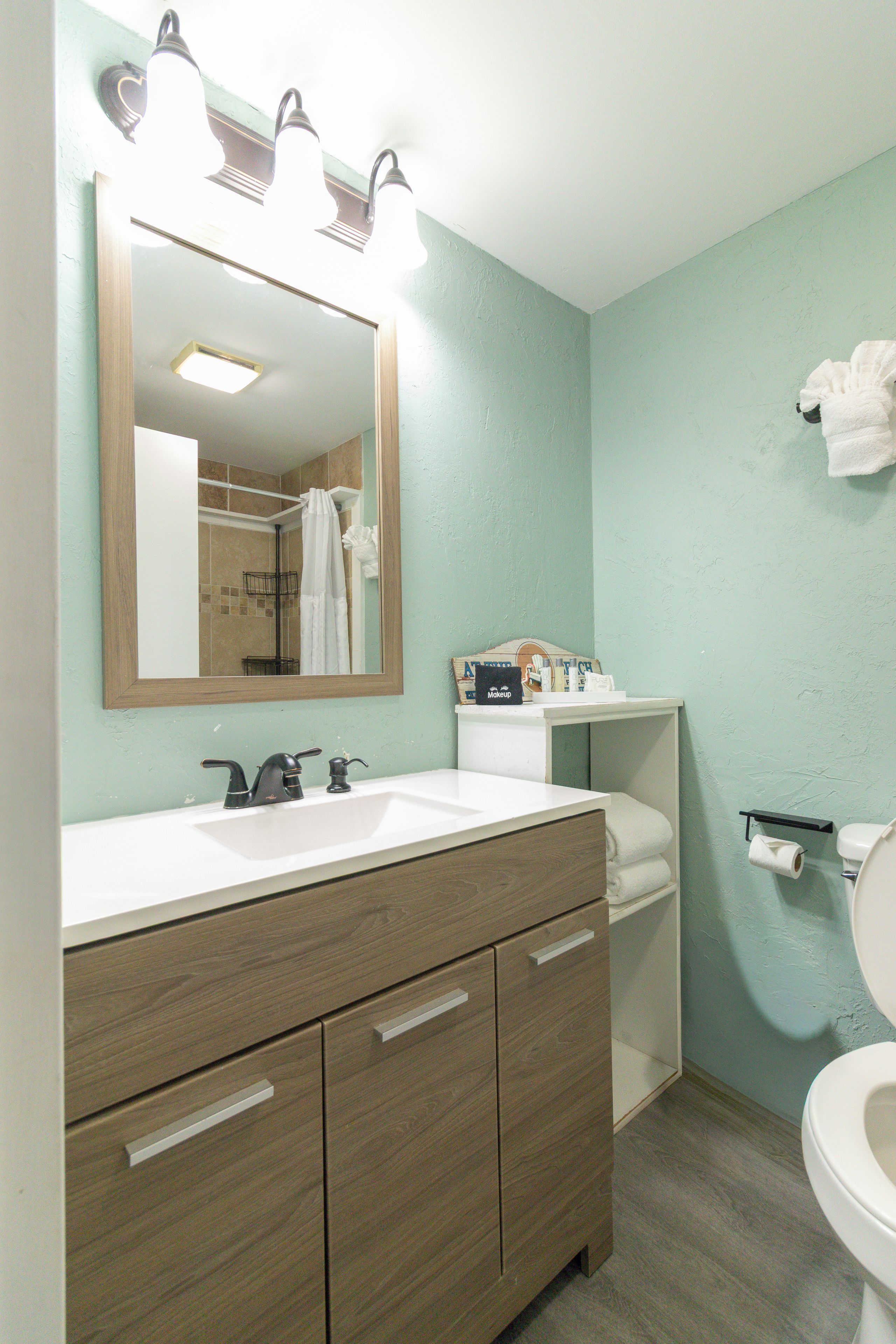 A bathroom with a wooden vanity, a mirror, a sink, and a toilet.