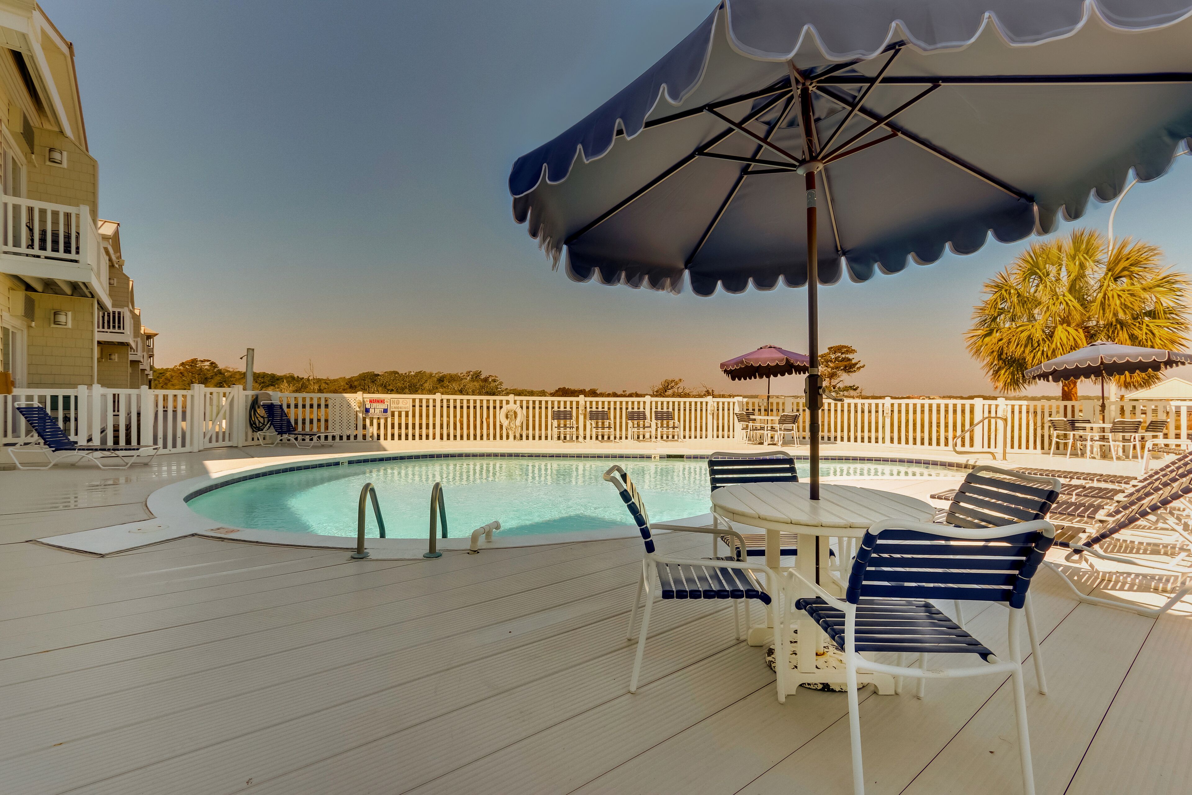 A poolside area with lounge chairs, umbrellas, and a pool.