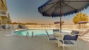 A poolside area with lounge chairs, umbrellas, and a pool.