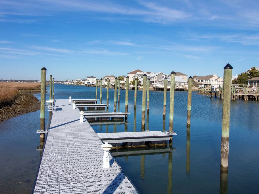 A waterfront pier with wooden posts and a metal walkway leading to docked boats.