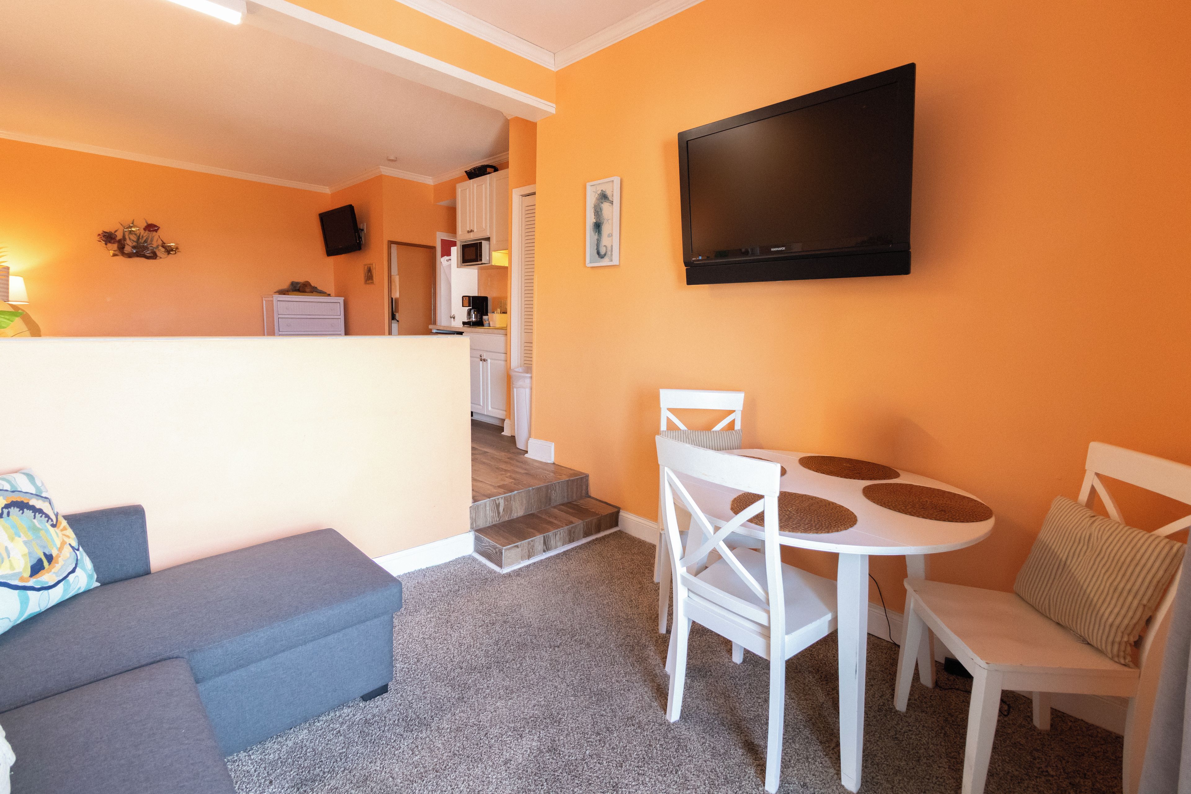 A compact living space with a kitchenette, a dining area with a table and chairs, and a seating area with a sofa.