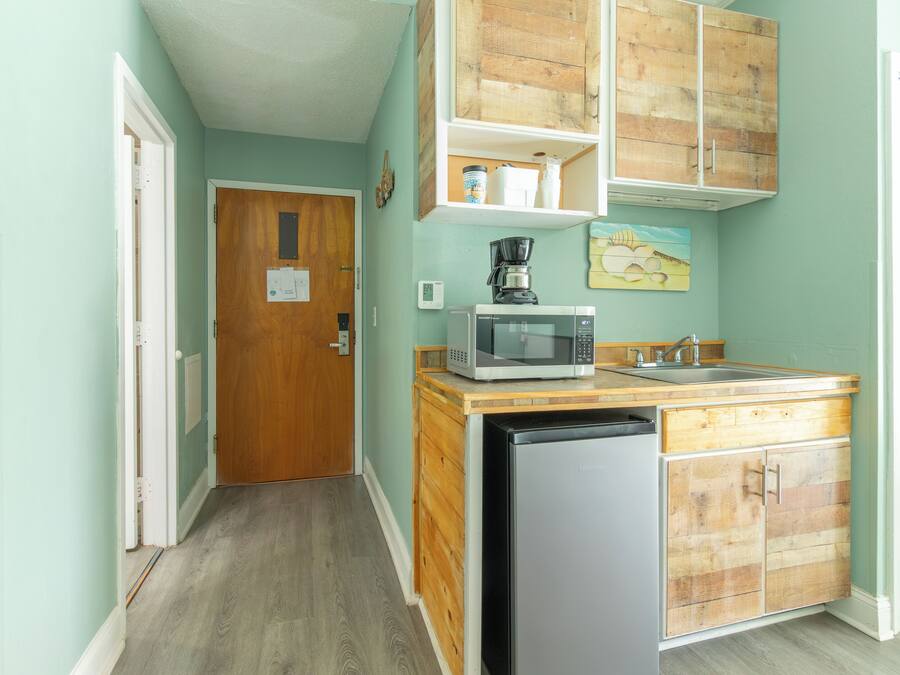 A compact kitchen with a dishwasher, microwave, and wooden cabinets.