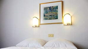 A hotel room with a bed, two wall-mounted light fixtures, and a framed painting above the bed. - Hotel Königshof The Arthouse (Cologne)