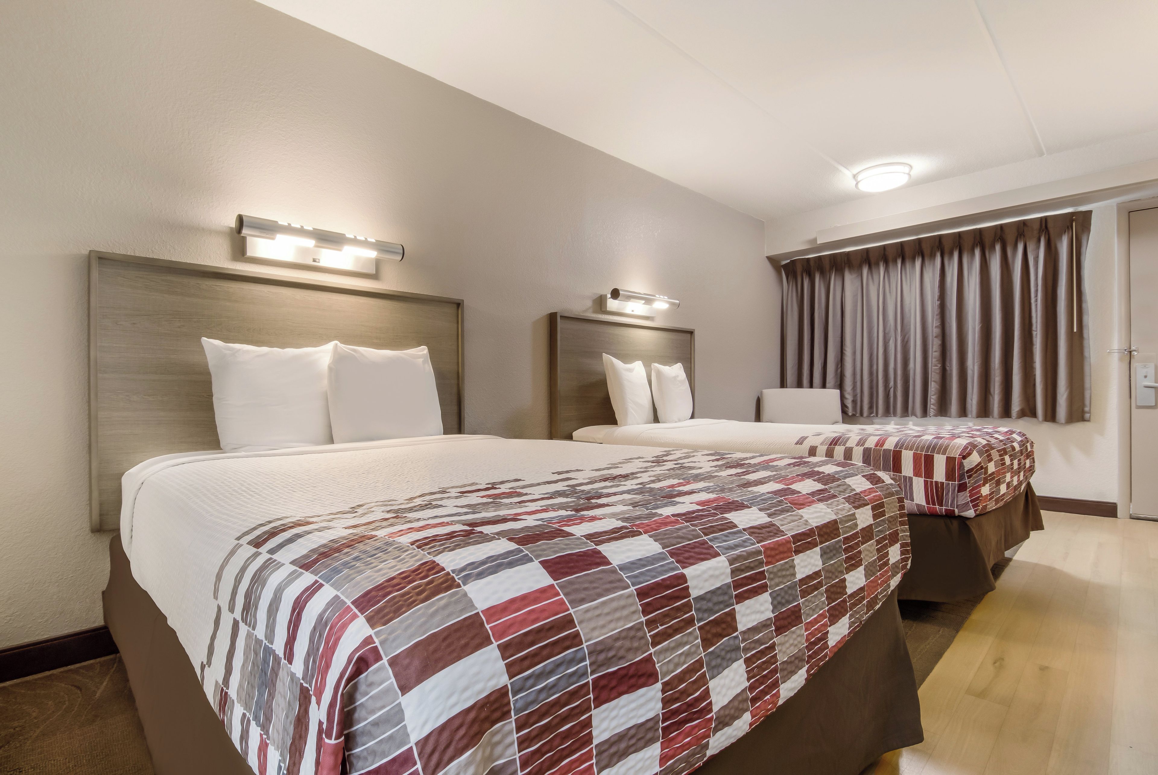 Habitación de hotel con dos camas, cada una con cabecera y lámparas de noche.