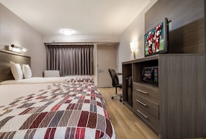 Una habitación de hotel con una cama grande, un escritorio con silla, un televisor y un microondas.