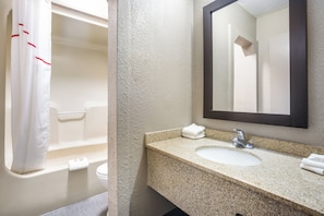 A bathroom with a bathtub, a sink, and a mirror. - Red Roof Inn Detroit - Farmington Hills (Farmington Hills)