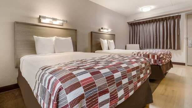 A hotel room with two beds, each with a headboard and bedside lamps. - Red Roof Inn Detroit - Farmington Hills (Farmington Hills)
