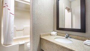 A bathroom with a bathtub, a sink, and a mirror. - Red Roof Inn Detroit - Farmington Hills (Farmington Hills)