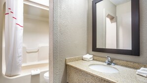 A bathroom with a bathtub, a sink, and a mirror. - Red Roof Inn Detroit - Farmington Hills (Farmington Hills)