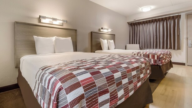 A hotel room with two beds, each with a headboard and bedside lamps. - Red Roof Inn Detroit - Farmington Hills (Farmington Hills)
