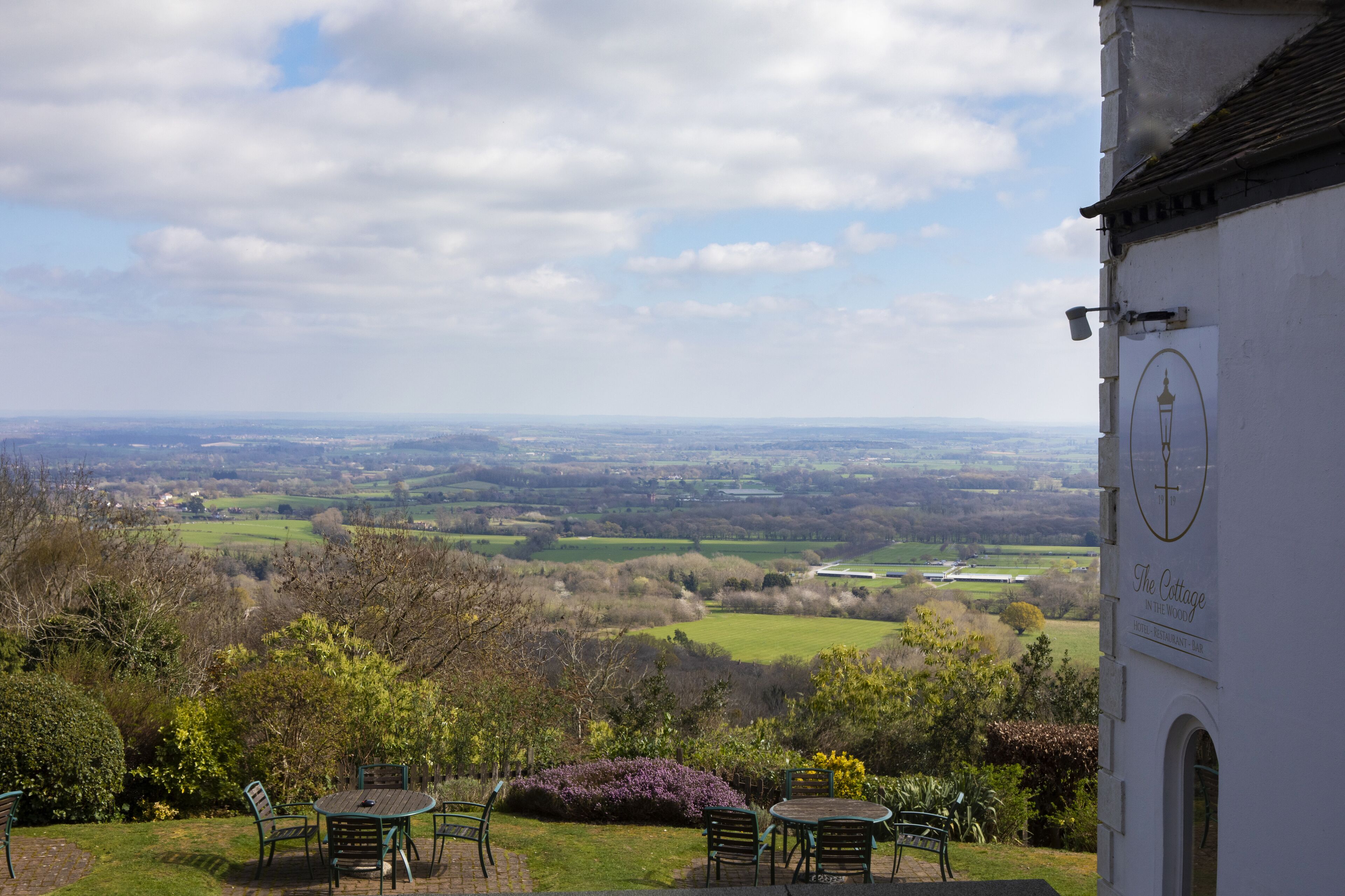 A view from a terrace with tables and chairs overlooking a valley.