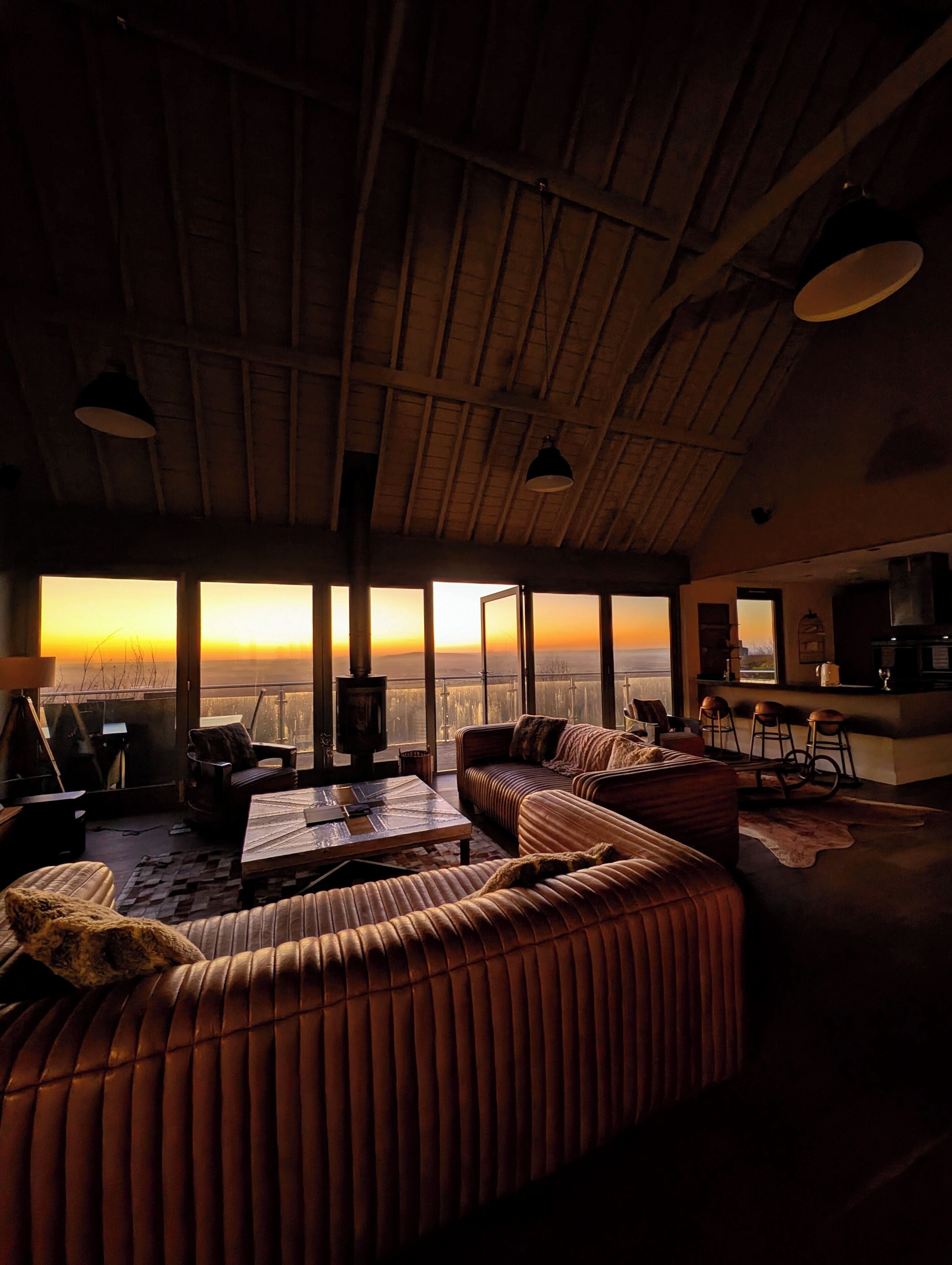 A cozy living room with a large window, a sofa, a coffee table, and a fireplace.