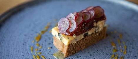 A slice of bread with cheese and radish slices on a blue plate.
