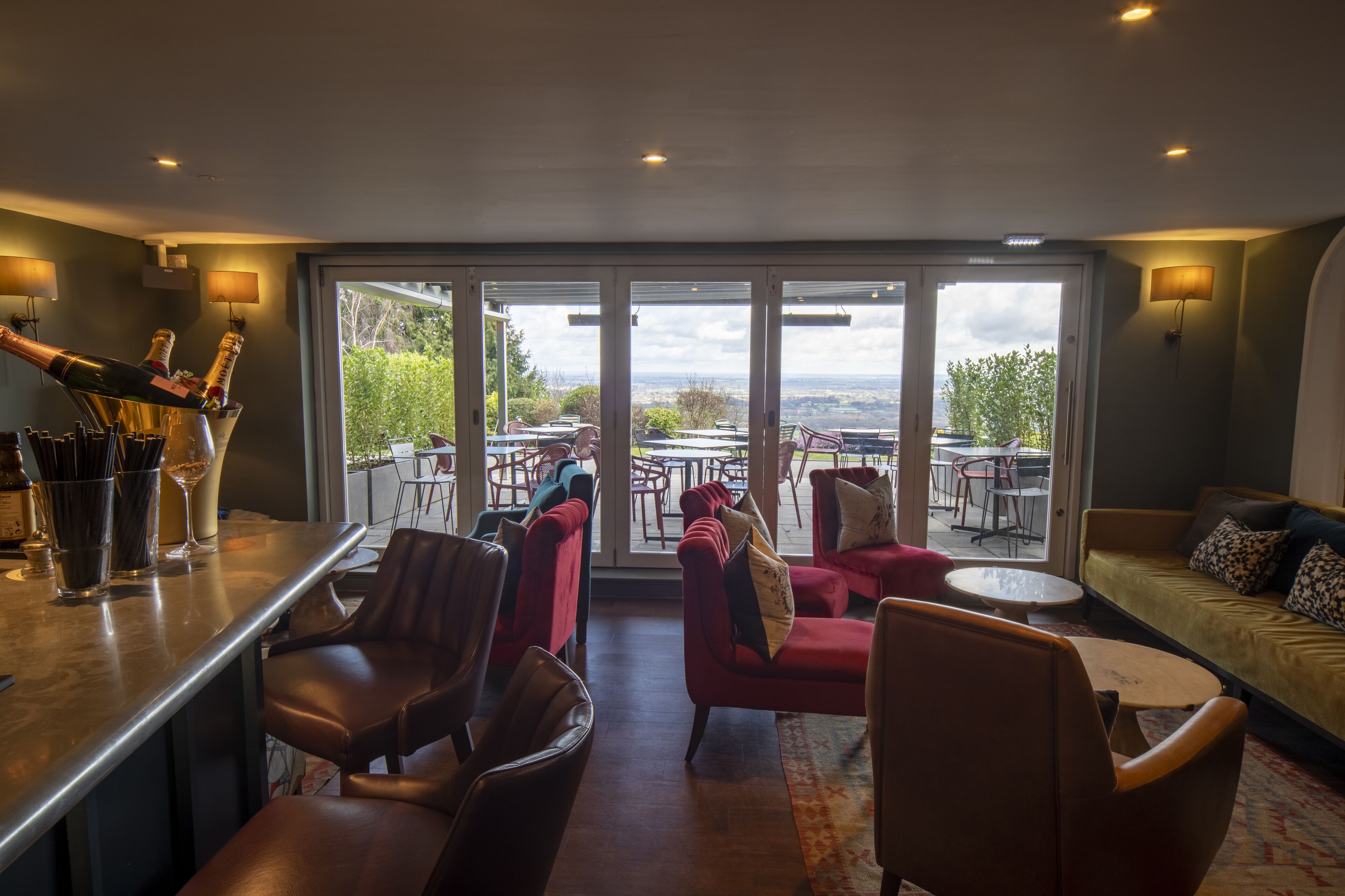 A bar area with a view of the outdoors, including a patio with tables and chairs.