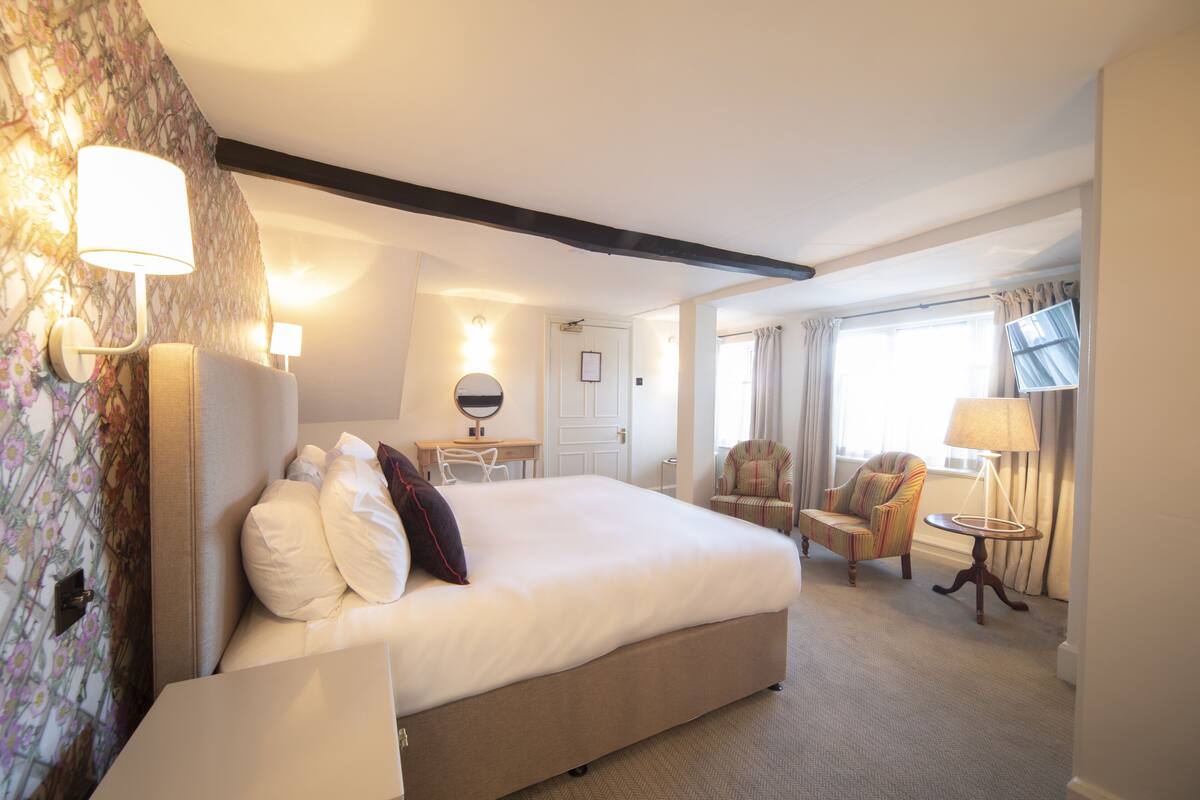 Une chambre d’hôtel avec un grand lit, un bureau, deux chaises, une télévision et une lampe.