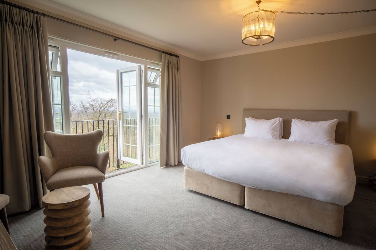 Une chambre d’hôtel avec un grand lit, une chaise et une vue par la fenêtre.